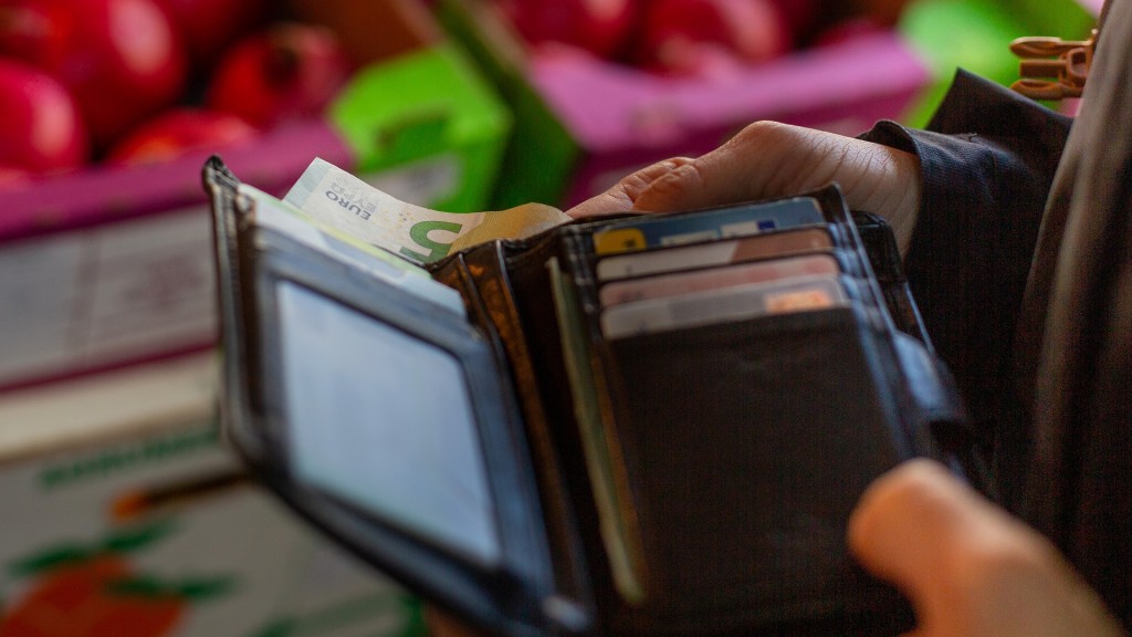 Foto: Eine Frau zieht einen Fünf-Euro-Schein aus ihrem Geldbeutel 