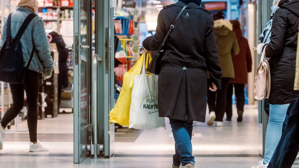 Kunden gehen mit Taschen durch ein Einkaufszentrum.