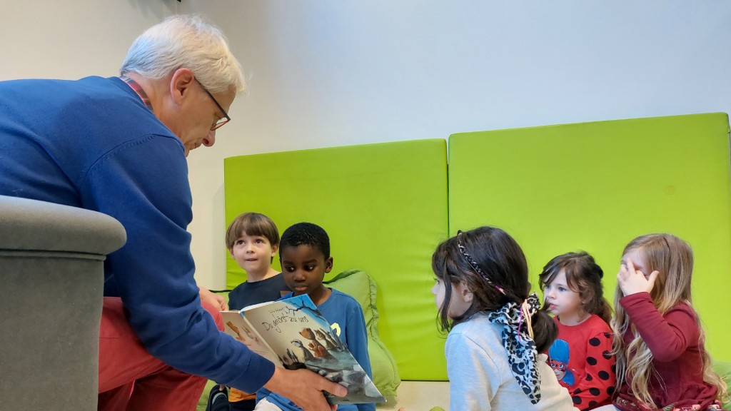 Vorlesepate Gerhard Flemig zeigt Kindern ein Buch