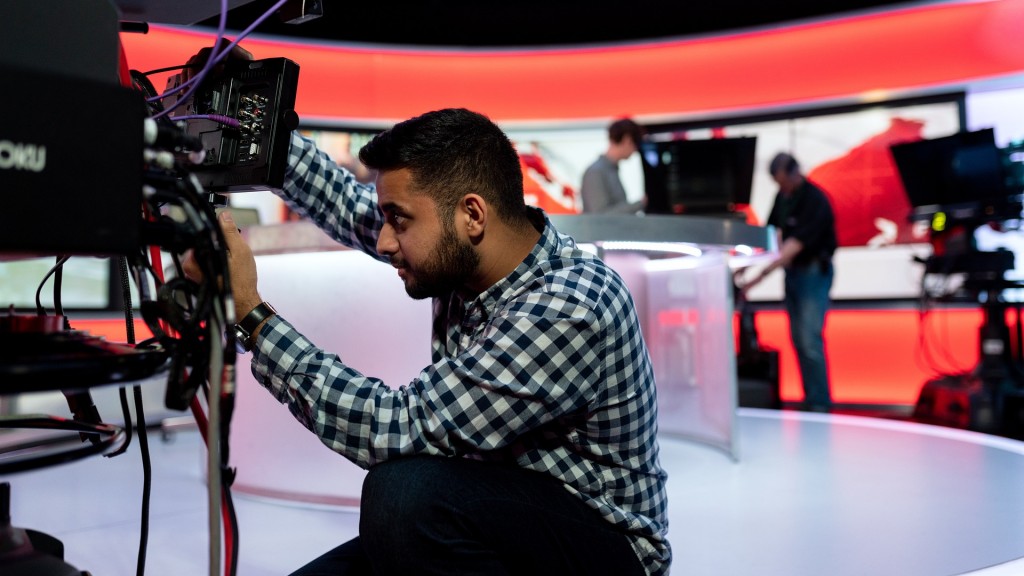 Ein Techniker an einer Kamera vor der Kulisse eines Fernsehstudios