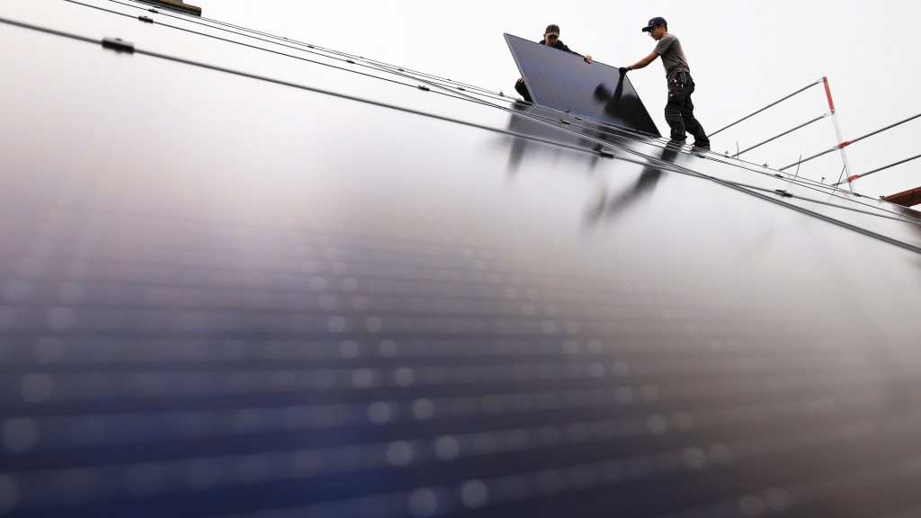 Handwerker montieren Solarmodule auf einem Dach.