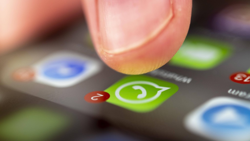 Finger tippt auf Bildschirm mit WhatsApp-Symbol.