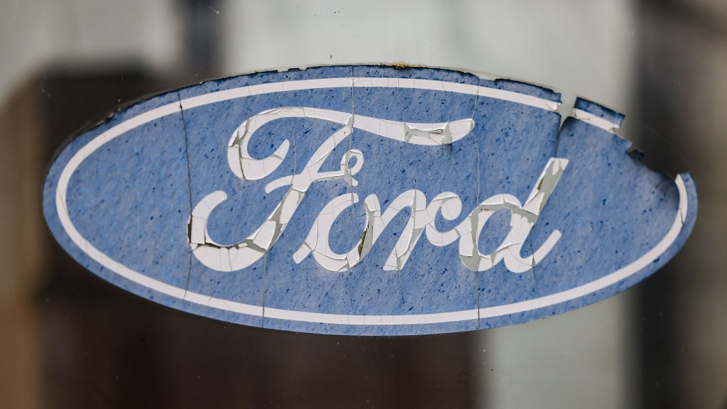 Ein abgeblättertes Logo von Ford hängt an einer Scheibe vor dem Werksgelände.
