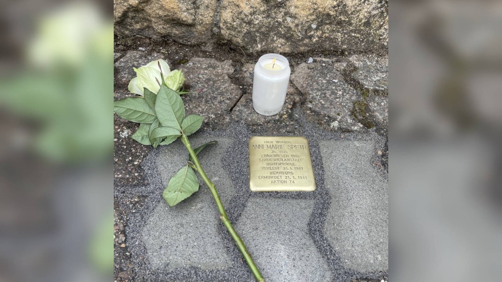 Stolperstein mit weißer Kerze und weißer Rose in Saarlouis