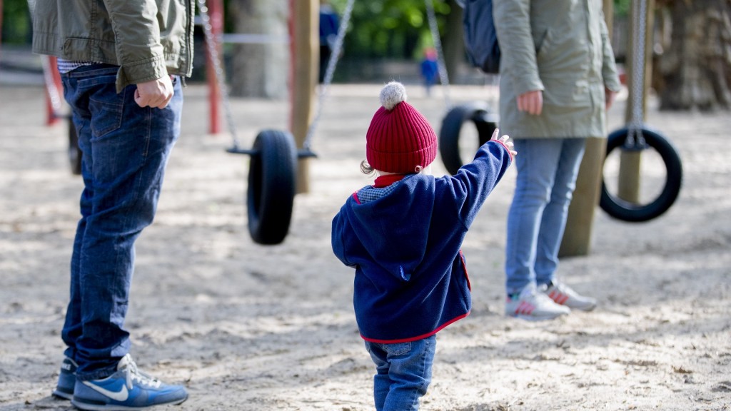 Ein Kind steht mit seinem Vater auf einem Spielplatz.