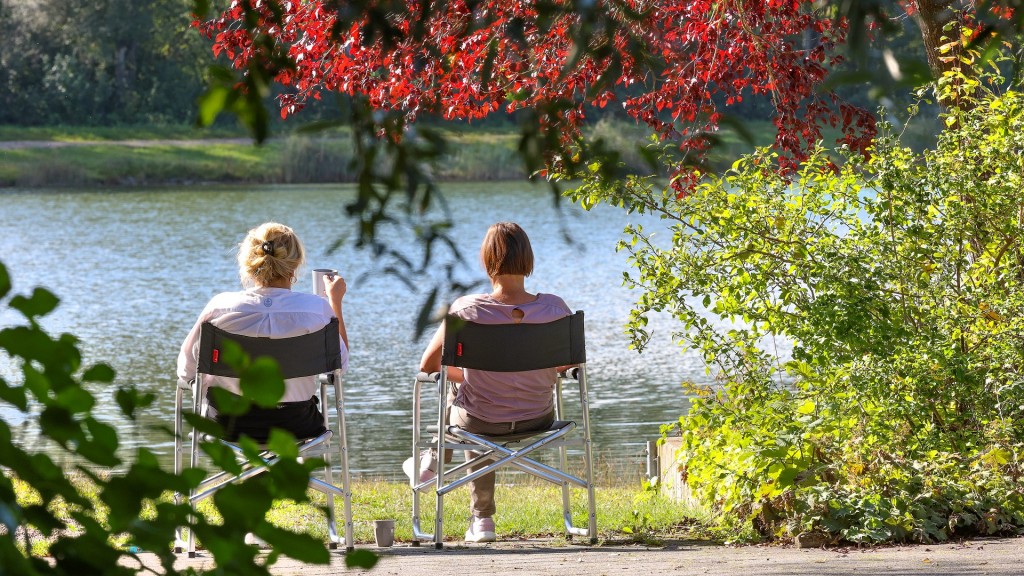 Zwei Frauen sitzen am Wasser in der Sonne