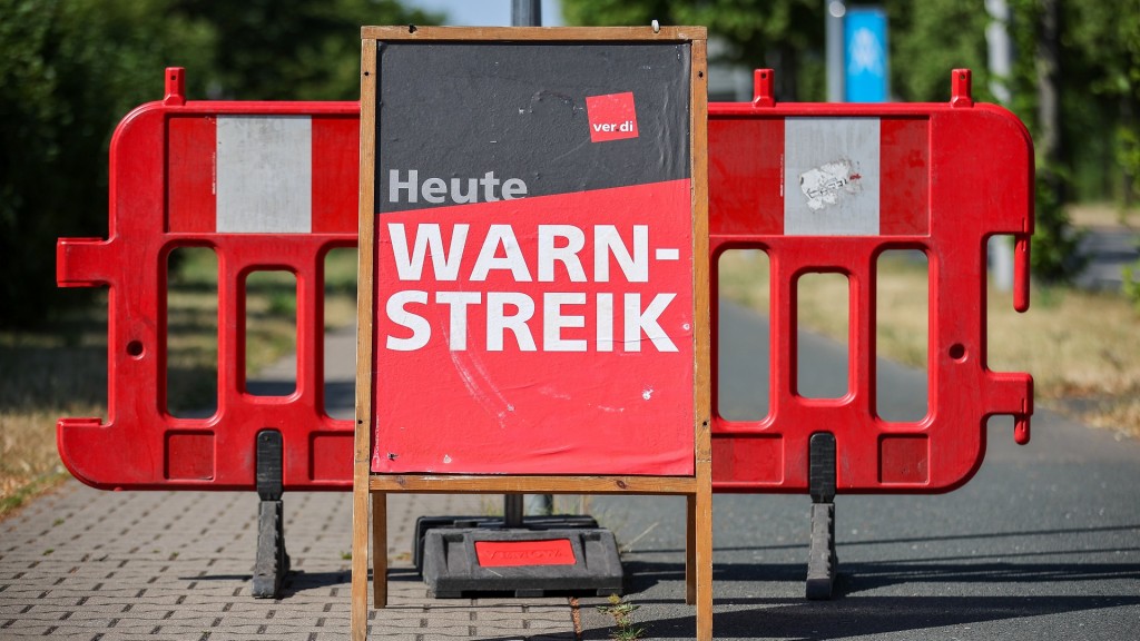 Foto: Ein Schild «Heute Warnstreik» steht auf der Straße vor einer Absperrung