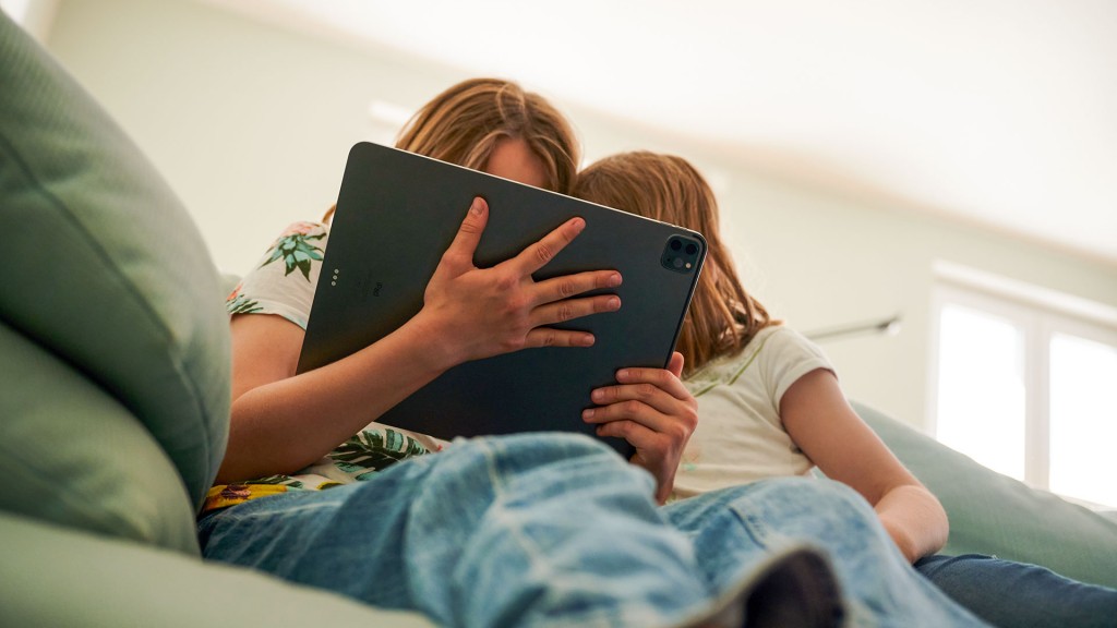 Zwei Kinder sitzen mit einem Tablet auf der Couch