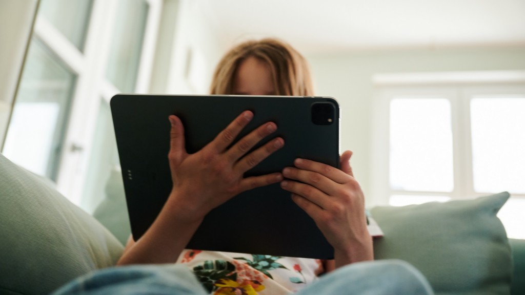 Mädchen sitzt mit einem Tablet auf der Couch