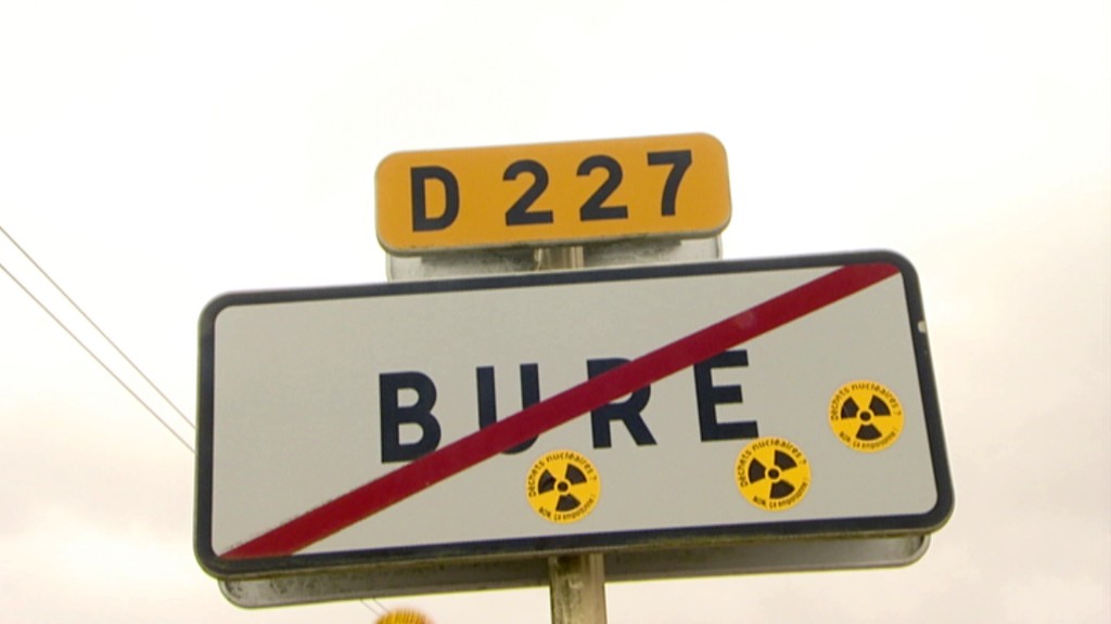 Ortsausgangsschild des Dörfchens Bure, auf das gelbe Aufkleber mit dem Zeichen für radioaktive Strahlung geklebt sind