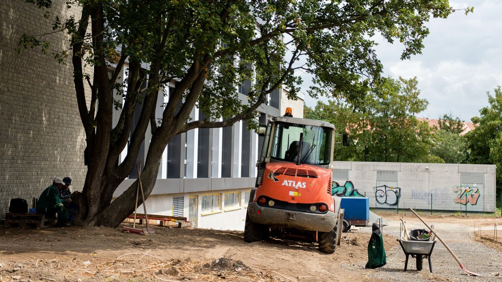 Ein Radlader steht auf der Baustelle vor einer Schule