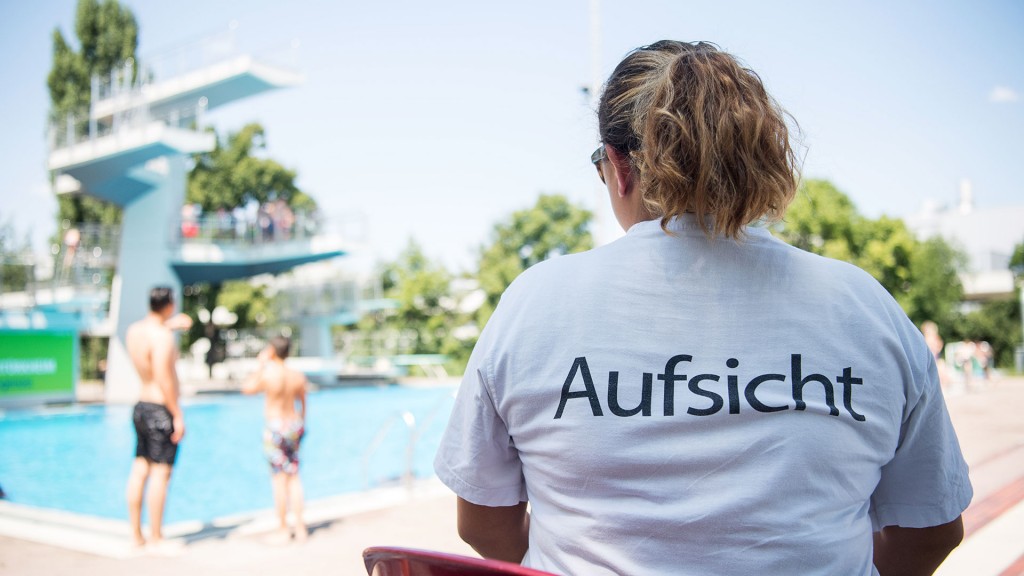 Eine Badeaufsicht beobachtet das Schwimmerbecken und den Sprungturm eines Freibades