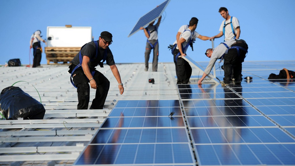 Installation von Solarmodulen einer Photovoltaik-Anlage auf dem Dach eines öffentlichen Gebäudes