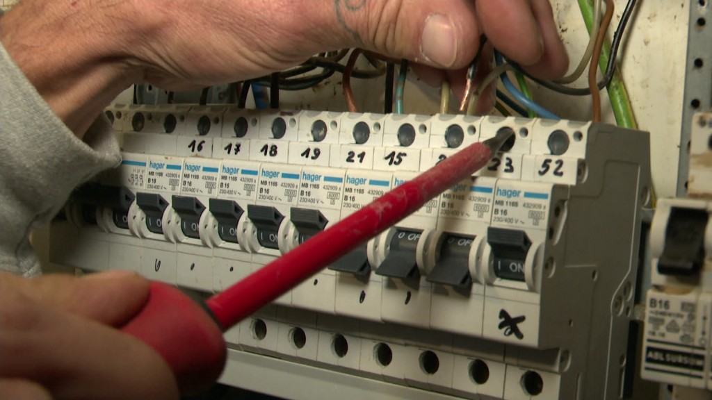 Ein Elektriker arbeitet an einem Stromkasten.