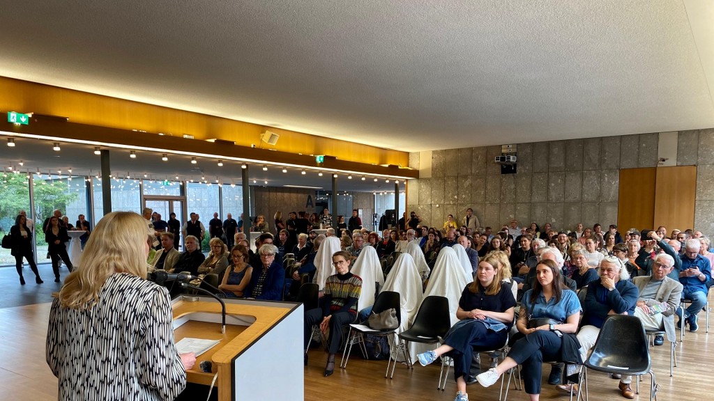Protestaktion der Künstlerin Sung-Hyung Cho: Sie und Mitstreiter bedeckten sich mit weißen Tüchern, als Kultusministerin Christine Streichert-Clivot (SPD, links am Pult) am 21. Juni eine Vernissage des Künstlers Daniel Hausig eröffnete.