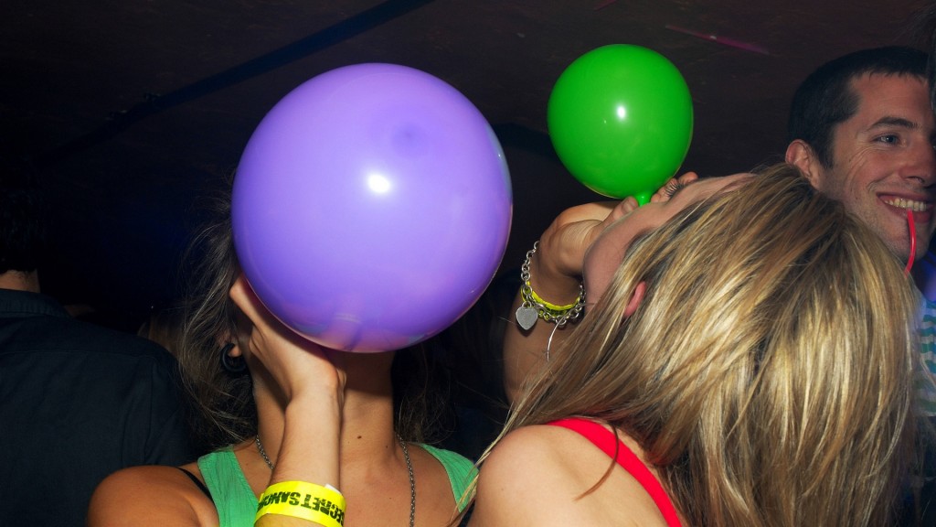 Jugendliche inhalieren auf einer Party Lachgas mit Hilfe von Ballons