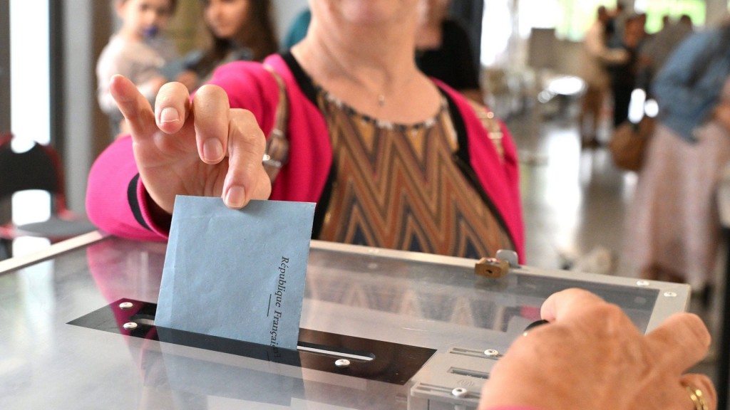 Foto: Eine Frau steckt den Wahlumschlag zur Parlamentswahl in die Wahlurne.
