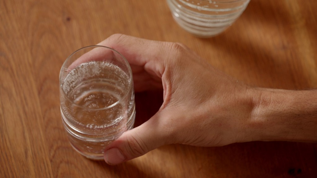 Eine Hand hält ein Glas Mineralwasser