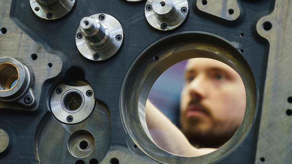 Ein Mitarbeiter im Maschinenbau montiert das Seitenteil eines Druckwerks