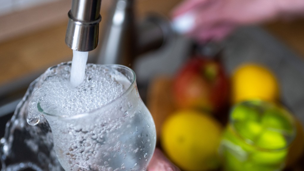 Tinkwasser läuft aus dem Wasserhahn in einer Küche in ein Glas