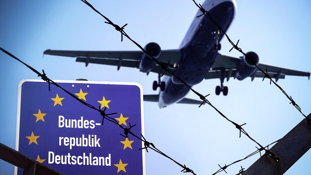 Foto: FOTOMONTAGE: Ein Flugzeug fliegt über einen Stacheldrahtzaun. 