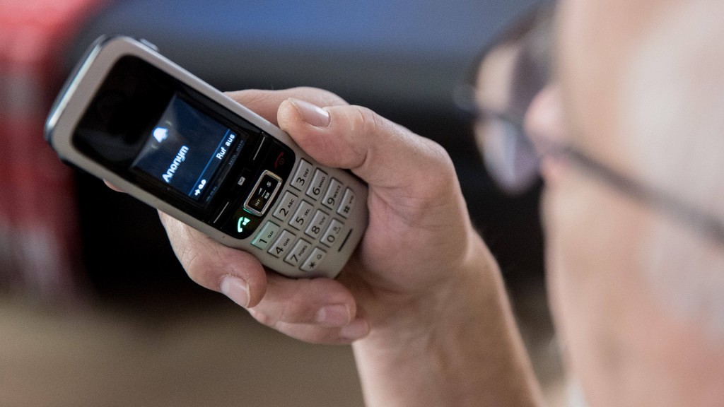 Foto: Ein älterer Menschen sitzt in seiner Wohnung und hält ein Telefon in der Hand.