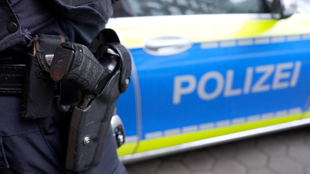 Foto: Ein Polizist steht vor einem Einsatzfahrzeug der Polizei.
