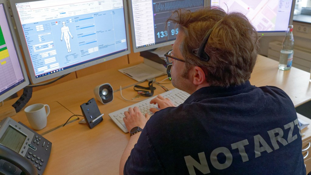 Ein Notarzt sitzt an seinem Arbeitsplatz in einer medizinischen Telefonzentrale