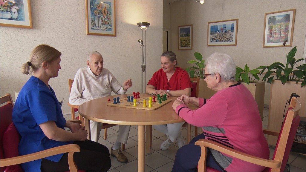 Foto: Ältere Menschen und eine Altenpflegerin spielen ein Brettspiel