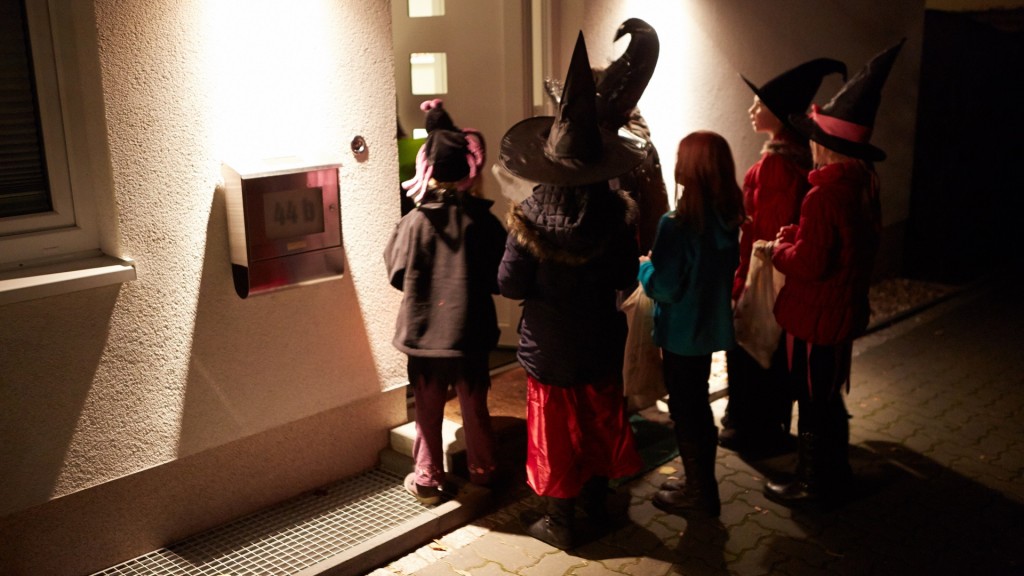 Kinder in Halloween-Kostümen sammeln am 31.10. an einer Haustür Süßigkeiten.