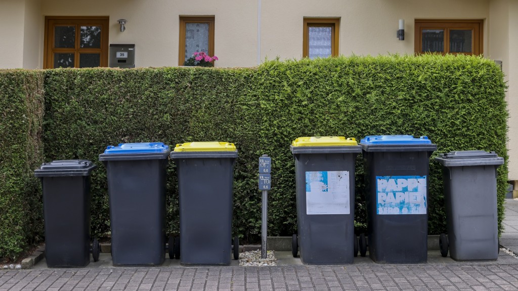 Verschiedene Mülltonnen stehen vor einem Haus.