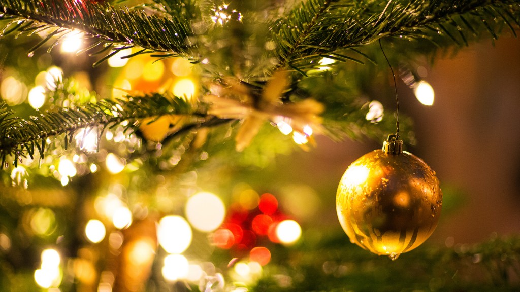 Foto: Eine goldene Kugel hängt an einem Weihnachtsbaum