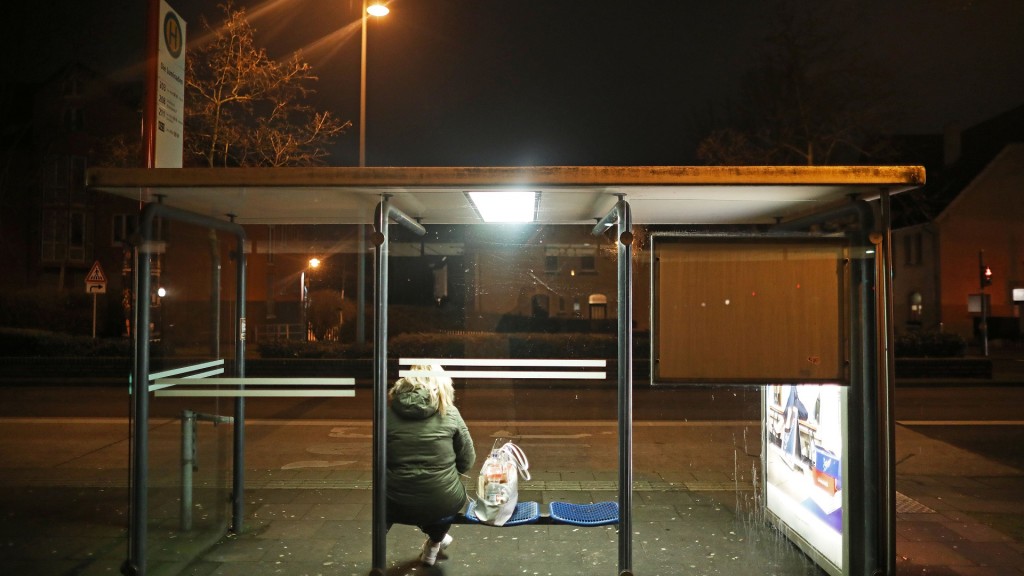 Frau wartet am Abend an einer Bushaltestelle