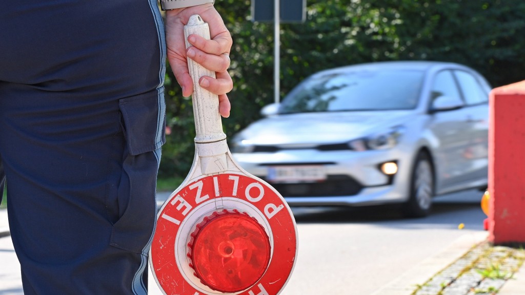 Ein Polizist hält an der Grenze eine Polizeikelle in der Hand