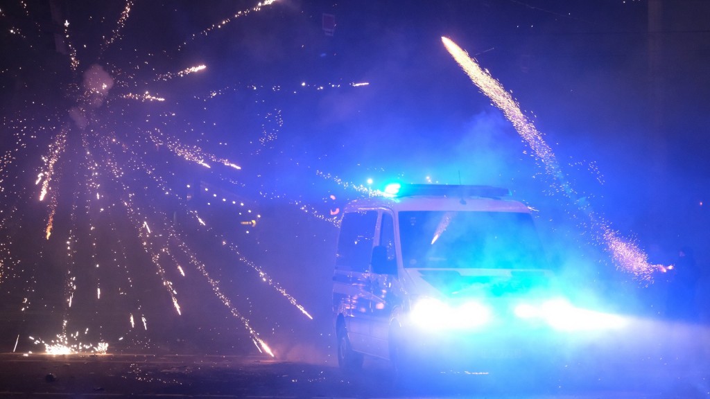 Foto: Ein Polizeifahrzeug fährt in der Silvesternacht an Feuerwerk vorbei.