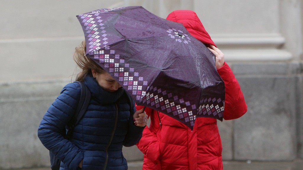 Frauen kämpfen bei Sturmböen mit ihrem Regenschirm 