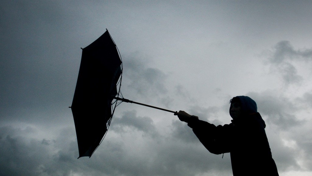 Eine Windböe erfasst den Regenschirm eines Spaziergängers.