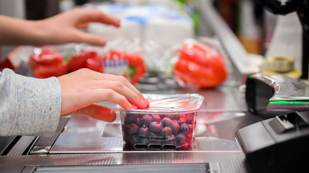 Eine Kassiererin schiebt Waren über die Supermarktkasse