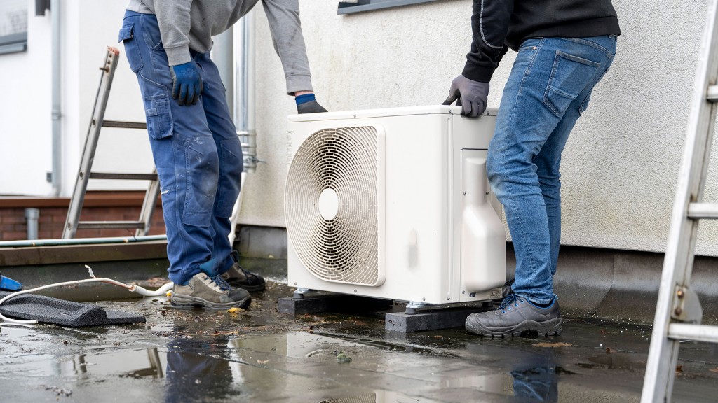 Zwei Fachhandwerker intallieren die Außeneinheit einer Wärmepumpenanlage an einem Wohnhaus