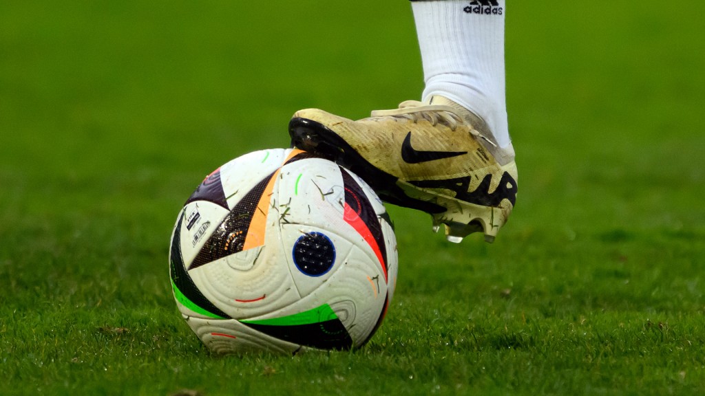 Ein Spieler hält einen Fußball mit dem Schuh