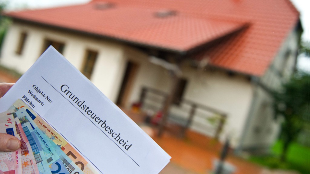 Grundsteuerbescheid vor ihrem Haus in der Hand