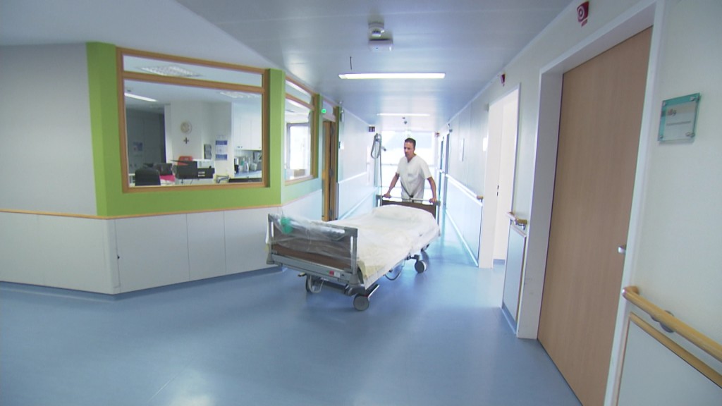 Ein Pfleger schiebt ein leeres Bett im Krankenhaus durch den Flur