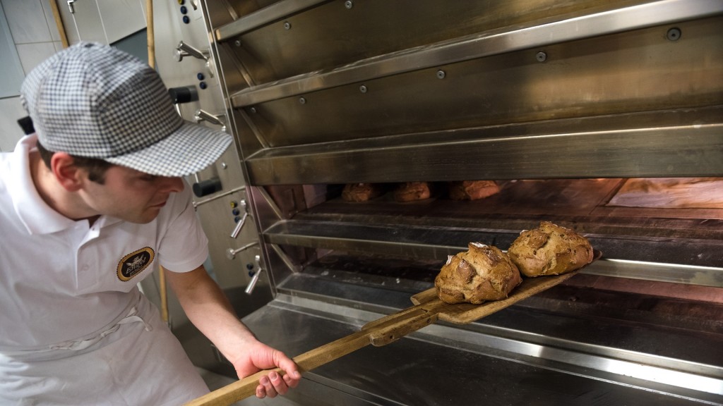 Ein Bäcker schiebt einen Laib Brot in den Ofen