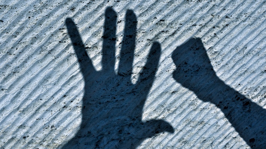 Foto: Schatten einer Faust und einer flachen Hand an einer Wand