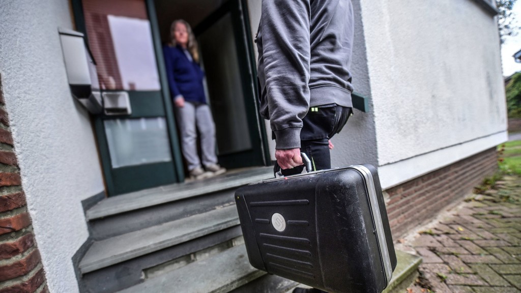 Ein Mann mit Werkzeugkoffer steht vor einer Haustür