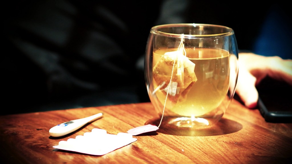 Tee, Tabletten und ein Fieberthermometer auf einem Tisch
