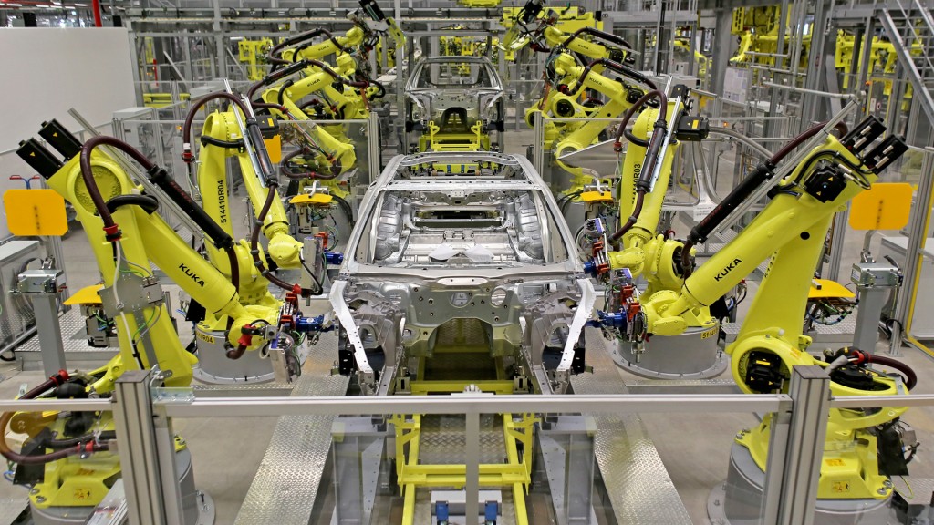  Mehrere Schweißroboter arbeiten an Karossen in einer Autofabrik.