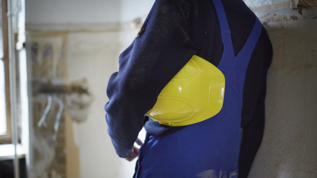 Ein Bauarbeiter macht Pause und hält den Schutzhelm unter dem Arm