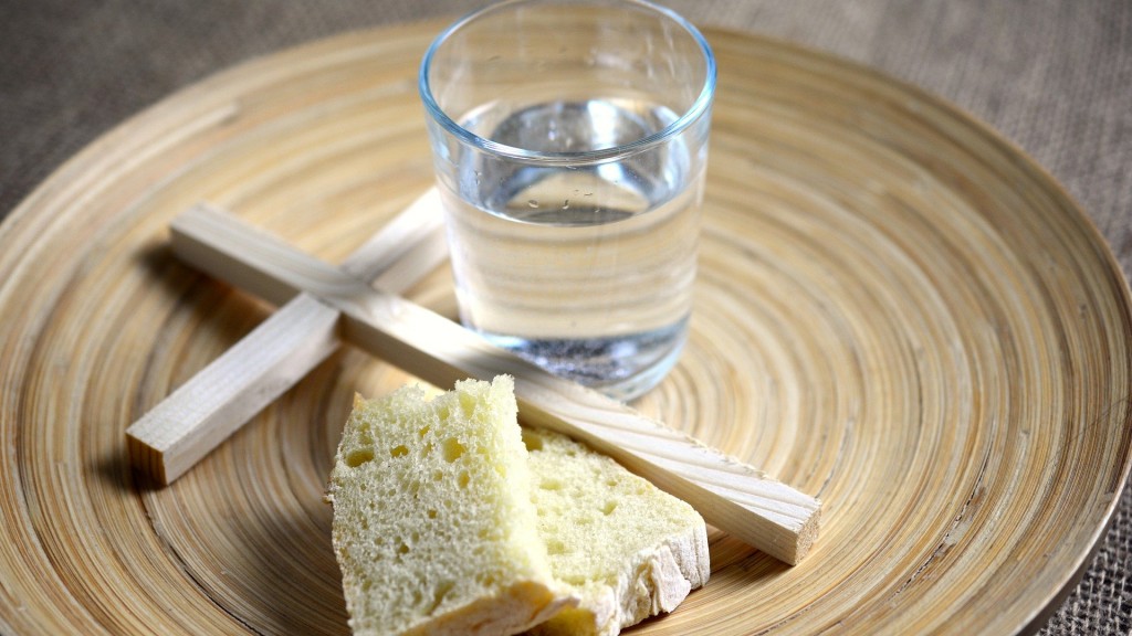 Brot neben einem Kreuz und einem Glas Wasser auf einem Teller