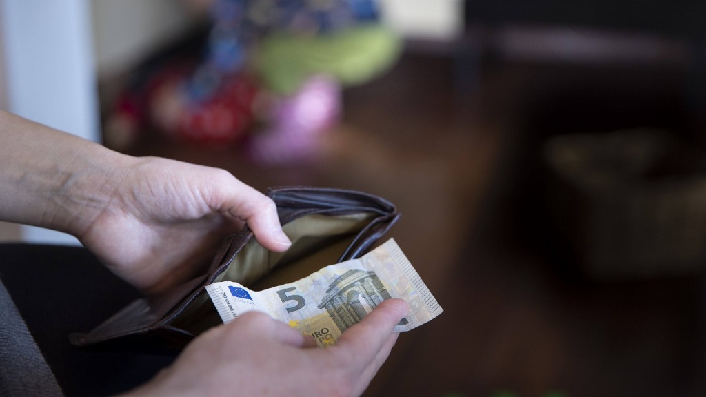 Eine Person nimmt einen Fünf-Euro-Schein aus einem ansonst leeren Geldbeutel.